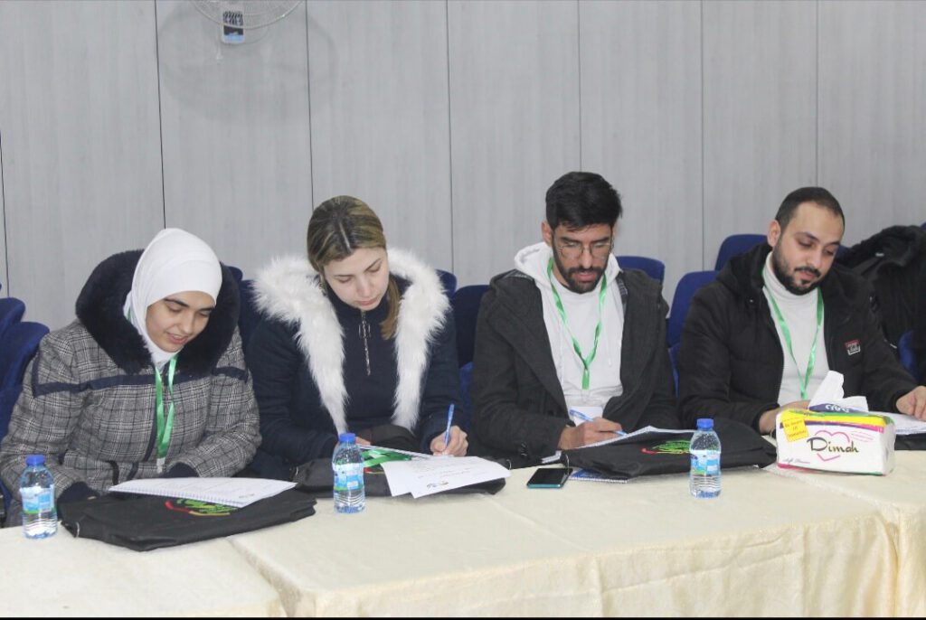 Vier medizinische Fachkräfte sitzen während einer Weiterbildung nebeneinander an einem Tisch und arbeiten konzentriert an ihren Unterlagen.